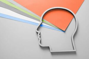 A minimalist outline of a human head in profile with colorful paper rays, symbolizing ideas and creativity, bursts from the top, set against a light gray background—perfect for an Autumn or October update theme.