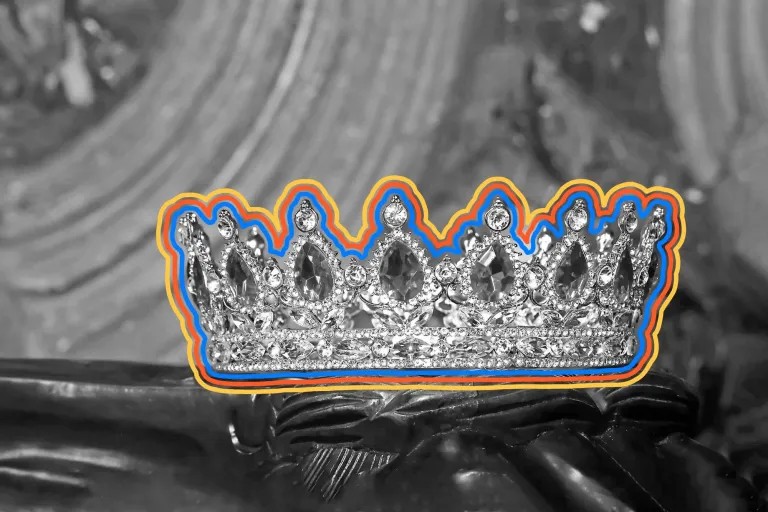 A sparkling diamond crown with blue and orange outlines rests on a black-and-white background featuring a statue’s hand and intricate carvings, capturing the elegance of July Journeys.