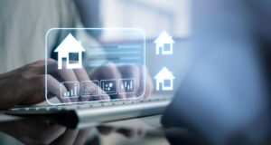 A person typing on a keyboard with virtual icons of houses, graphs, and data charts overlaid, symbolizing Flathead Valley’s online real estate or property management technology during the busy Spring Market.