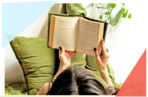 A person with dark hair lies on green cushions, holding an open book above their face. A green plant hangs in the background, while pastel blue and red geometric shapes frame the corners—capturing a quiet August Reflections moment.