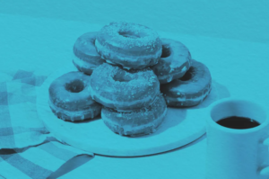 A stack of glazed donuts is arranged on a round wooden board, with a coffee mug and checkered napkin nearby. The image has a blue overlay, adding a touch of Winter Glow to this cozy scene.