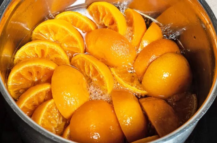 Orange slices simmering in a pot of liquid, much like the zest and vibrancy sought after during summer listing season—perfect for marmalade or candied orange peel.
