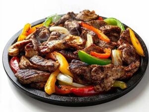 A sizzling plate of grilled beef strips mixed with red, yellow, and green bell peppers and onions captures the Season of Action, served on a black platter against a white background. Steam rises from the hot, freshly cooked food.